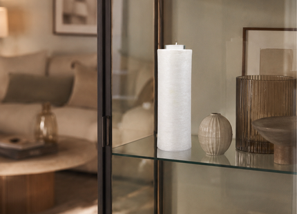 Weiße DIY Kerze mit Teelichteinsatz dekorativ in einer Glasvitrine im Wohnzimmer präsentiert