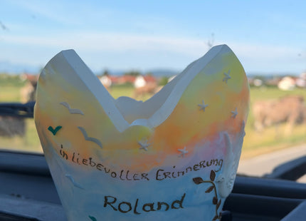 Personalisierter Lichtfang aus Wachs vor grüner Wiese und Allgäuer Bergpanorama- vom Auto aus.
