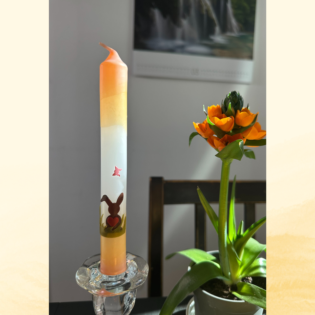 Handdekorierte Oster Stabkerze mit Hasenmotiv in Apricot-Weiß-Grün im Glasständer als frühlingshafte Tischdekoration