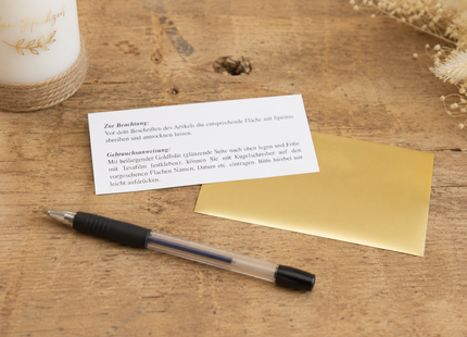 Goldene Kerzen Beschriftungsfolie mit Kugelschreiber auf Arbeitstisch für DIY Kerzenverzierung