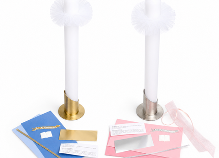 Zwei DIY Kommunionkerzen Bastelsets im Vergleich auf weißem Hintergrund: links das Set in Blau und Gold, rechts das Set in Rosa und Silber, jeweils mit weißem Kerzenrohling, Metallständer, Wachsplatten, Wachsfäden, Echtwachs-Schild, Buchmotiv, Folie und Tüll.