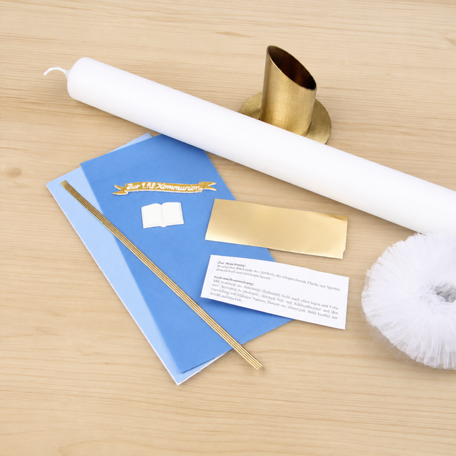 Detailansicht des blau-goldenen Kommunionkerzen Bastelsets mit liegendem Kerzenrohling, goldfarbenem Kerzenständer, blauen Wachsplatten, Goldfolie, Wachsfäden, Echtwachs-Schild, Buchmotiv und Tüll.