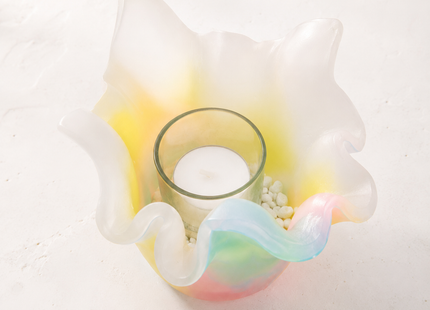 Nahaufnahme eines Lotus-Lichtfangs aus Wachs mit Teelichtglas, weißem Kies und zarten Aurora-Borealis-Farben