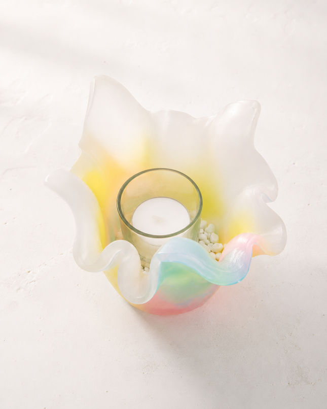Nahaufnahme eines Lotus-Lichtfangs aus Wachs mit Teelichtglas, weißem Kies und zarten Aurora-Borealis-Farben