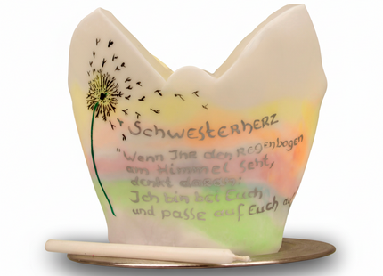 Handgefertigter Lichtfang aus Wachs mit Pusteblume und pastellfarbenem Verlauf auf einem goldfarbenen Teller.