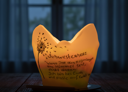 Von innen beleuchteter Pusteblumen-Lichtfang vor einem Fenster am Abend.