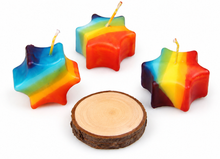 Kleine bunte Sternkerze im Regenbogen-Stil auf natürlicher Holzscheibe als Glücksstern und Hoffnungslicht.
