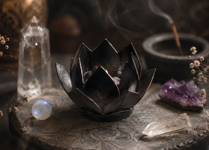 Schwarzes Lotus-Windlicht mit brennendem Teelicht in mystischer Atmosphäre mit Kristallen, Mondlicht und dunkler Ritualstimmung.