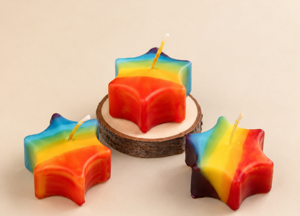 Regenbogen-Sternkerzen Set mit drei kleinen Sternkerzen und Holzteller in heller Produktansicht von oben.