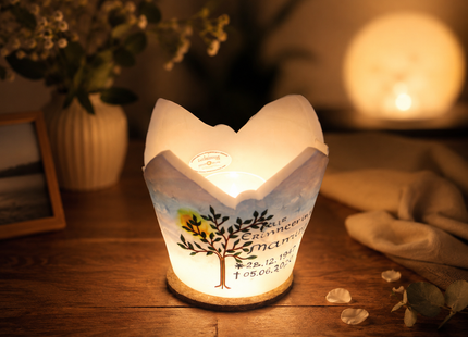 Geöffnetes Trauerlicht aus Wachs mit sichtbarem Teelicht, Lebensbaum-Motiv und sanftem Lichtschein am Abend.