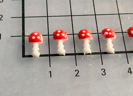 Mini-Glückspilze aus Wachs werden mit einem kleinen Klebewachs-Klecks auf Kerzen befestigt