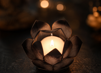 Brennendes schwarzes mini Lotus-Windlicht, bei dem das Kerzenlicht sanft und warm durch die dunklen, transparenten Lotusblätter schimmert.