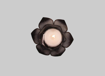 Brennendes schwarzes Lotus-Windlicht, bei dem das Kerzenlicht sanft und warm durch die dunklen, transparenten Lotusblätter schimmert.