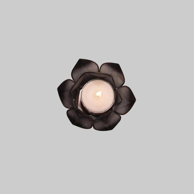 Brennendes schwarzes Lotus-Windlicht, bei dem das Kerzenlicht sanft und warm durch die dunklen, transparenten Lotusblätter schimmert.